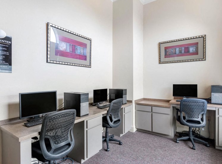 Business Center with computer lab, three chairs, framed photos on the walls, and tan and cream desks